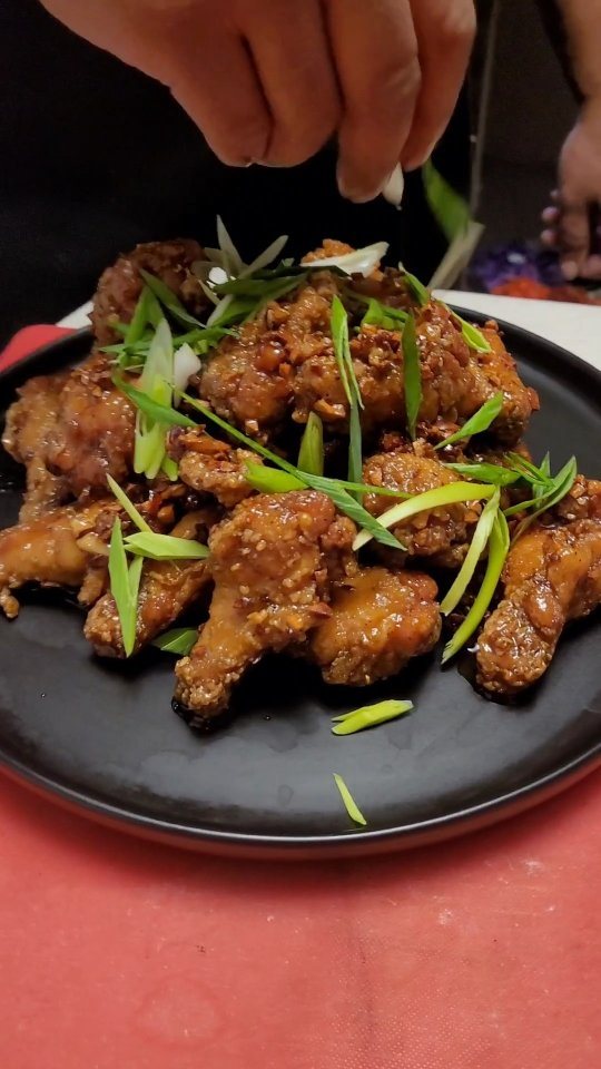 Ailes de poulet garnies à la main sur assiette noire